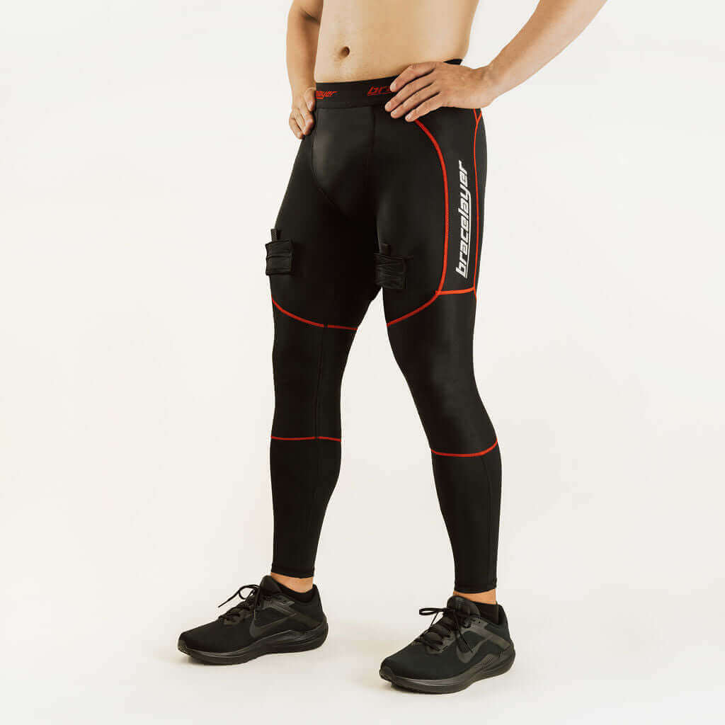 Black hockey compression pants with red piping and knee support pads, standing view