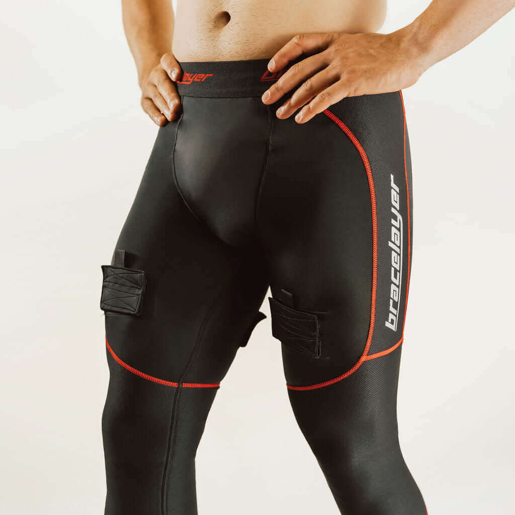 Black hockey compression pants with red piping and padded knee panels, front view
