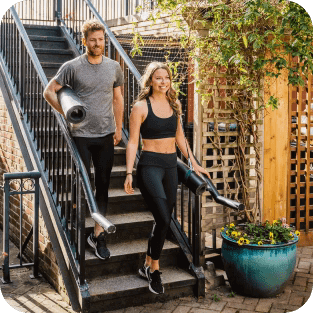 A photo of two people heading down stairs after a yoga class, wearing stylish Bracelayer KS1 compression leggings with knee support.