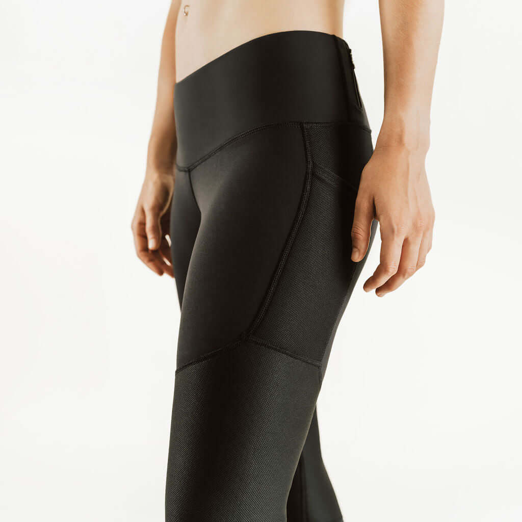 Black compression pants detail: curved seam panels and knee support section.